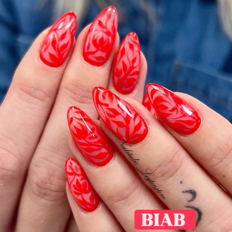 Glossy red BIAB nails with a swirled rose pattern