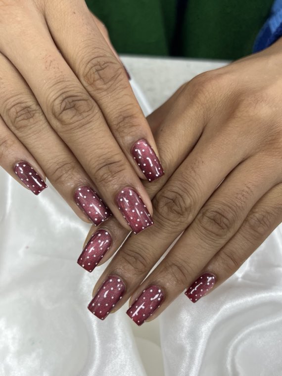 Deep burgundy cat-eye nails with white polka-dot detail